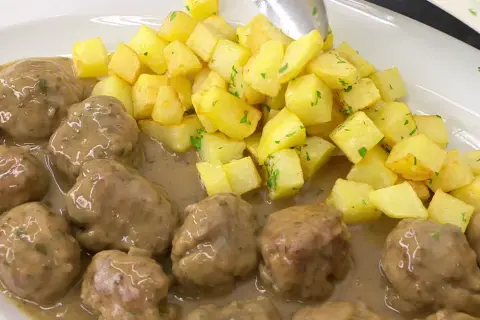 Albóndigas en salsa arguiñano, jugosas y tiernas, acompañadas de patatas fritas doradas y perejil picado. ¡Un plato casero irresistible!