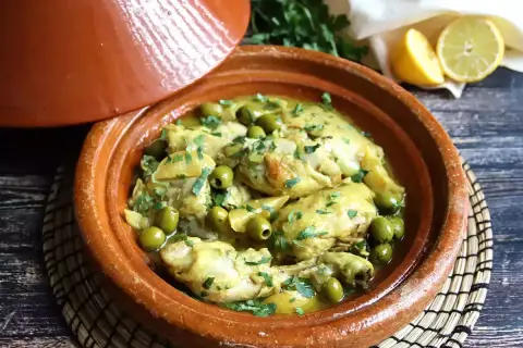 Tajín de pollo con aceitunas verdes y limón, servido en una cazuela de barro tradicional.