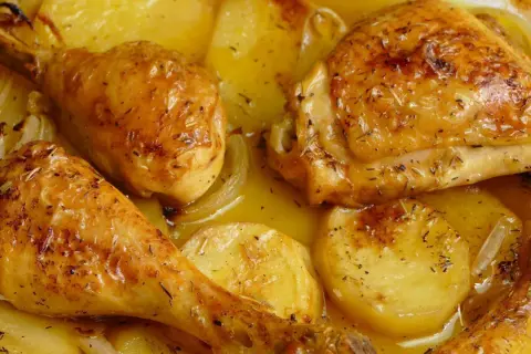 Pollo al horno dorado y jugoso, con patatas y cebolla, todo bañado en su propio jugo. ¡Un festín para la vista y el paladar!