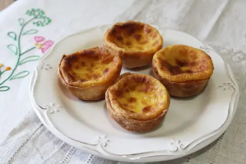 Cuatro pastelitos de arroz dorados y cremosos en un plato blanco, listos para ser disfrutados.