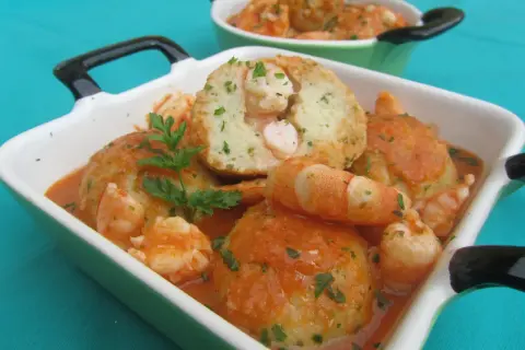 Albondigas de rape con gambas en salsa, servidas en cazuelas verdes y blancas, decoradas con perejil fresco.