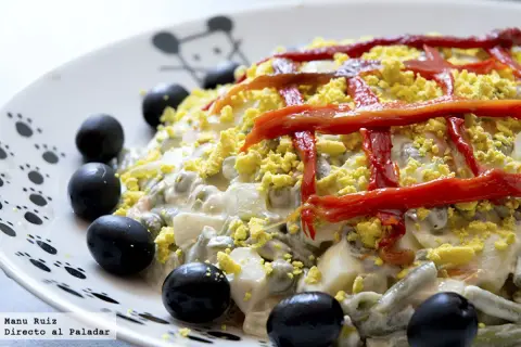 Ensaladilla rusa Thermomix cremosa, decorada con pimientos rojos y aceitunas negras. ¡Perfecta para cualquier ocasión!