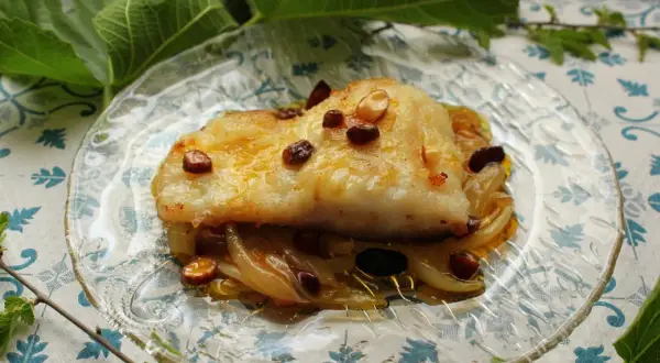 Filete de bacalao dorado sobre cebolla caramelizada y pasas. Una de las mejores recetas de bacalao.