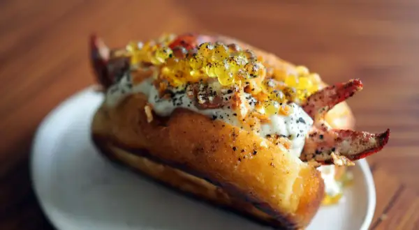Un delicioso lobster roll receta, con carne de cangrejo, caviar y salsa cremosa en un pan tostado.