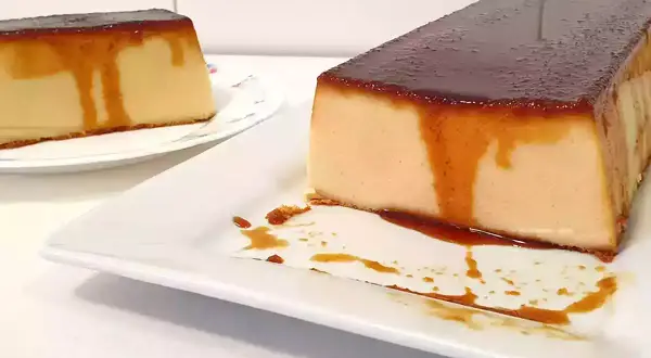 Dos porciones de pudin de pan con caramelo líquido, una en primer plano y otra al fondo.