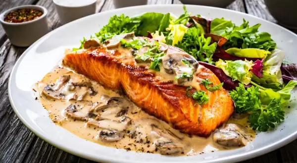 Salmón cremoso con champiñones, una de las mejores recetas con salmón, acompañado de ensalada fresca.