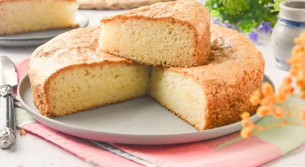 Bizcocho sin huevo esponjoso y dorado, servido en un plato gris con un cuchillo de plata. Perfecto para un postre ligero.
