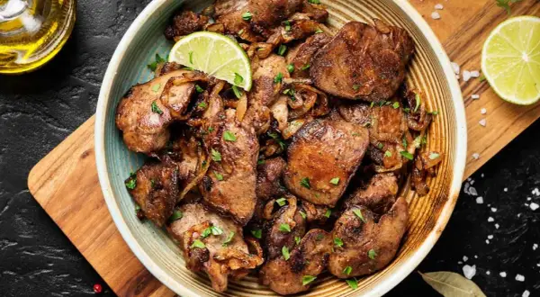 Sabrosos higaditos de pollo encebollados, salpicados de perejil fresco y adornados con rodajas de lima. Un plato casero irresistible.