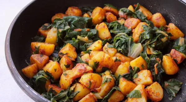 Acelgas con patatas doradas y tiernas, cocinadas en sartén. Un plato casero lleno de sabor y color.