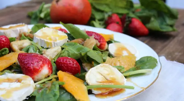 Deliciosa ensalada de espinacas con fresas, naranja, queso de cabra y nueces, bañada en aderezo dulce.