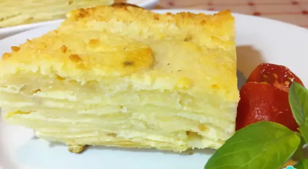 Delicioso pastel de papa en capas, un milhojas de patata gratinado, servido con tomates y albahaca.