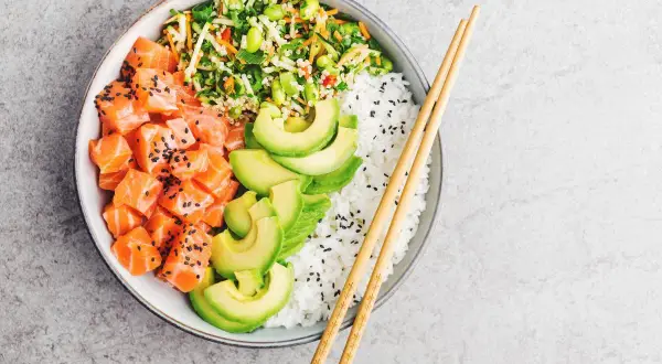 Un delicioso poke de salmón con aguacate, arroz blanco y vegetales frescos.