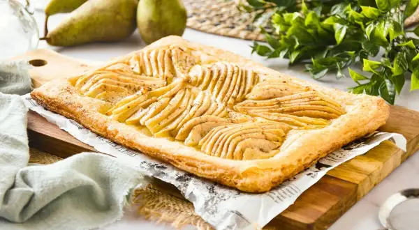 Deliciosa tarta de pera y hojaldre, con finas láminas de pera dispuestas sobre una base dorada y crujiente.
