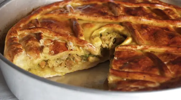 Empanada de carne dorada y crujiente, con un relleno jugoso visible en un corte. Perfecta para compartir.