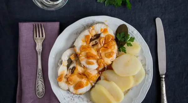 Merluza a la gallega servida con patatas cocidas y perejil. Un plato tradicional gallego.