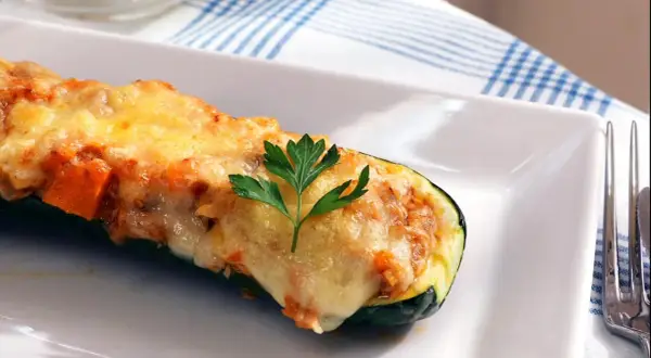 Calabacines rellenos de atún, gratinados con queso y decorados con perejil. Un plato delicioso y saludable.