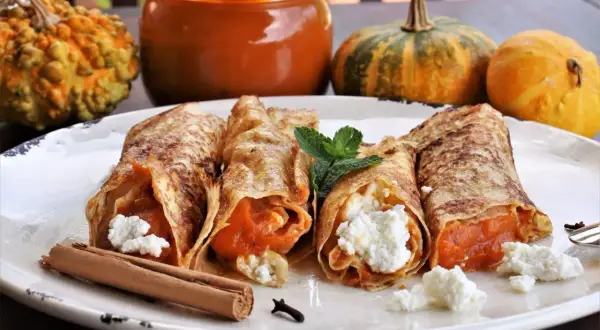 Rollitos de crepes rellenos de calabaza y queso fresco, decorados con menta y canela. Ideales para recetas con calabaza.