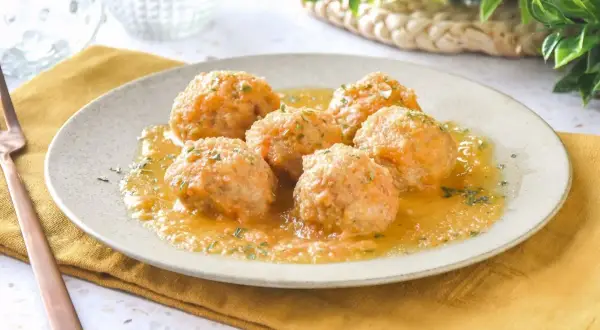 Sabrosas albóndigas de pollo en salsa, servidas en un plato con perejil picado. Un plato casero y reconfortante.