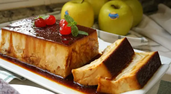 Delicioso pudin de manzana con caramelo, decorado con cerezas y menta. Manzanas verdes al fondo.