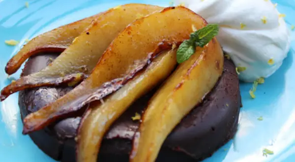 Deliciosa marquesa de chocolate con peras caramelizadas y crema batida, adornada con menta y ralladura de limón.