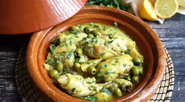 Tajín de pollo con aceitunas verdes y limón, servido en una cazuela de barro tradicional.