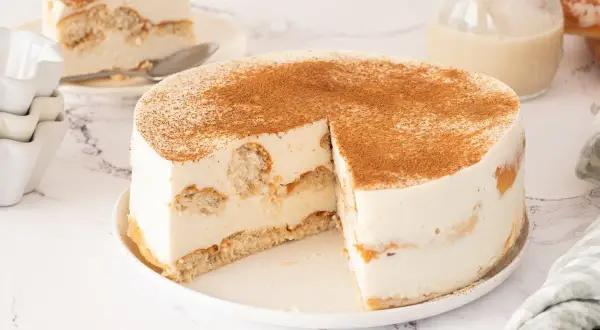 Tarta de horchata y fartons, con bizcocho y crema, espolvoreada con canela. Una porción ya servida.