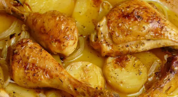 Pollo al horno dorado y jugoso, con patatas y cebolla, todo bañado en su propio jugo. ¡Un festín para la vista y el paladar!