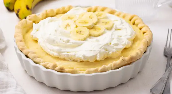 Deliciosa tarta de plátano con crema batida y rodajas de plátano fresco.