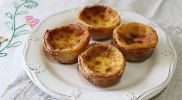 Cuatro pastelitos de arroz dorados y cremosos en un plato blanco, listos para ser disfrutados.