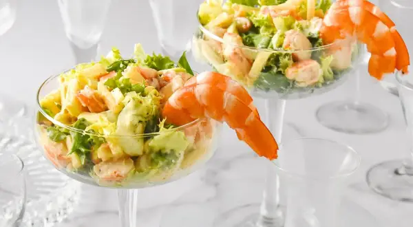 Delicioso coctel de gambas servido en copas elegantes, adornado con gambas enteras.