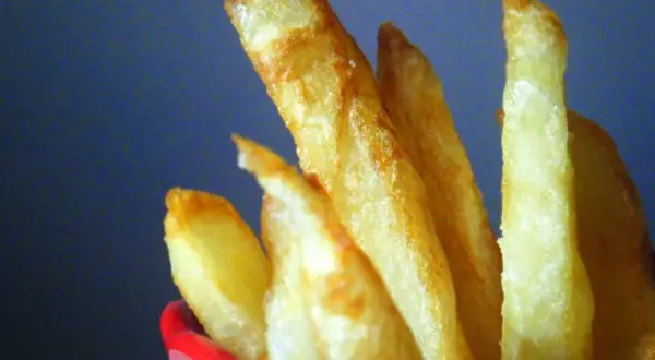 Patatas fritas doradas y crujientes en un recipiente rojo.
