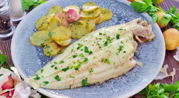 Delicioso lenguado al horno con patatas asadas y perejil fresco. Un plato principal ligero y sabroso.