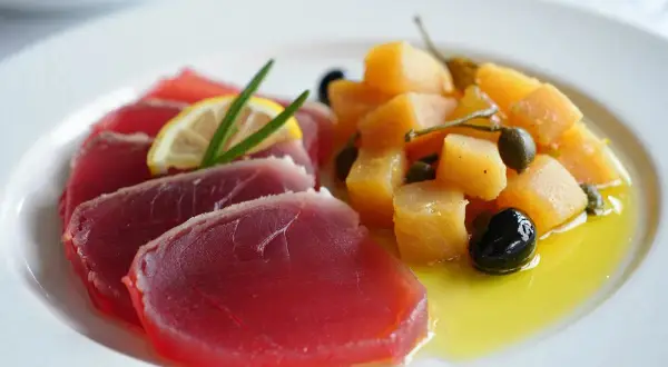 Deliciosa ventresca de atún cruda, servida con patatas, aceitunas y alcaparras en aceite de oliva.