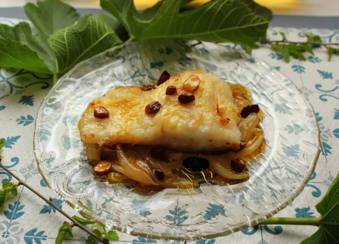 Filete de bacalao dorado sobre cebolla caramelizada y pasas. Una de las mejores recetas de bacalao.
