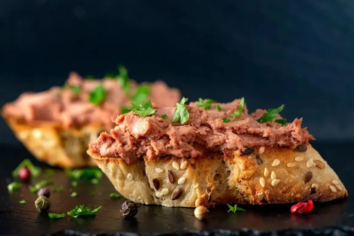 Rebanadas de pan rústico con un generoso untado de paté de hígado de pollo, decorado con perejil fresco y granos de pimienta.