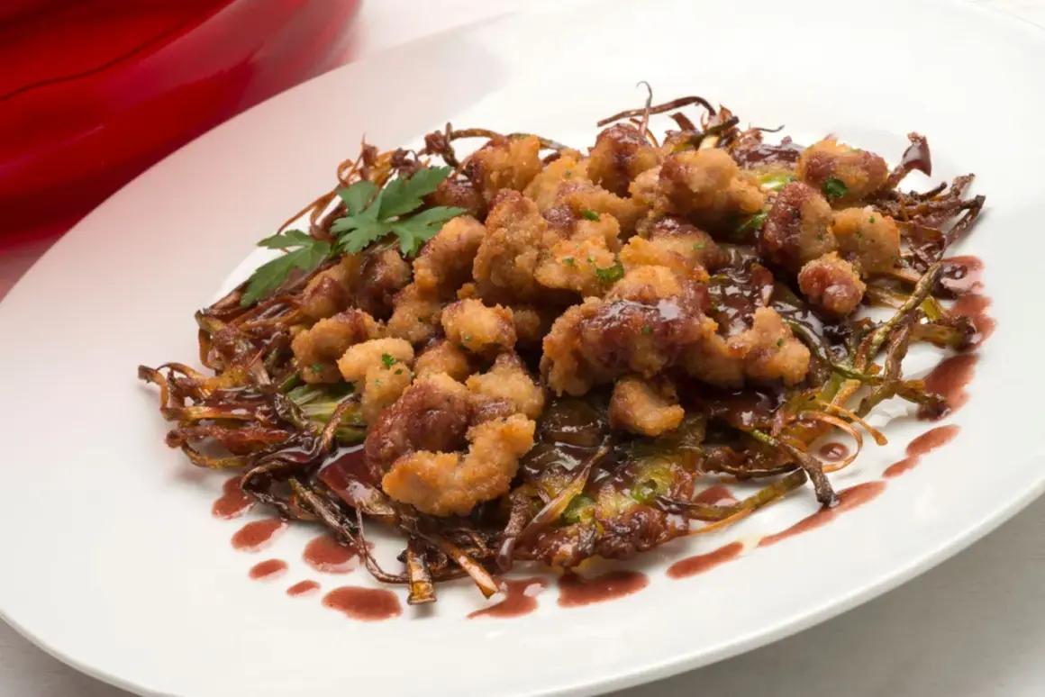 Mollejas de cordero rebozadas y crujientes, servidas sobre verduras salteadas y bañadas en una salsa oscura. ¡Una delicia para aprender como hacer mollejas de cordero!