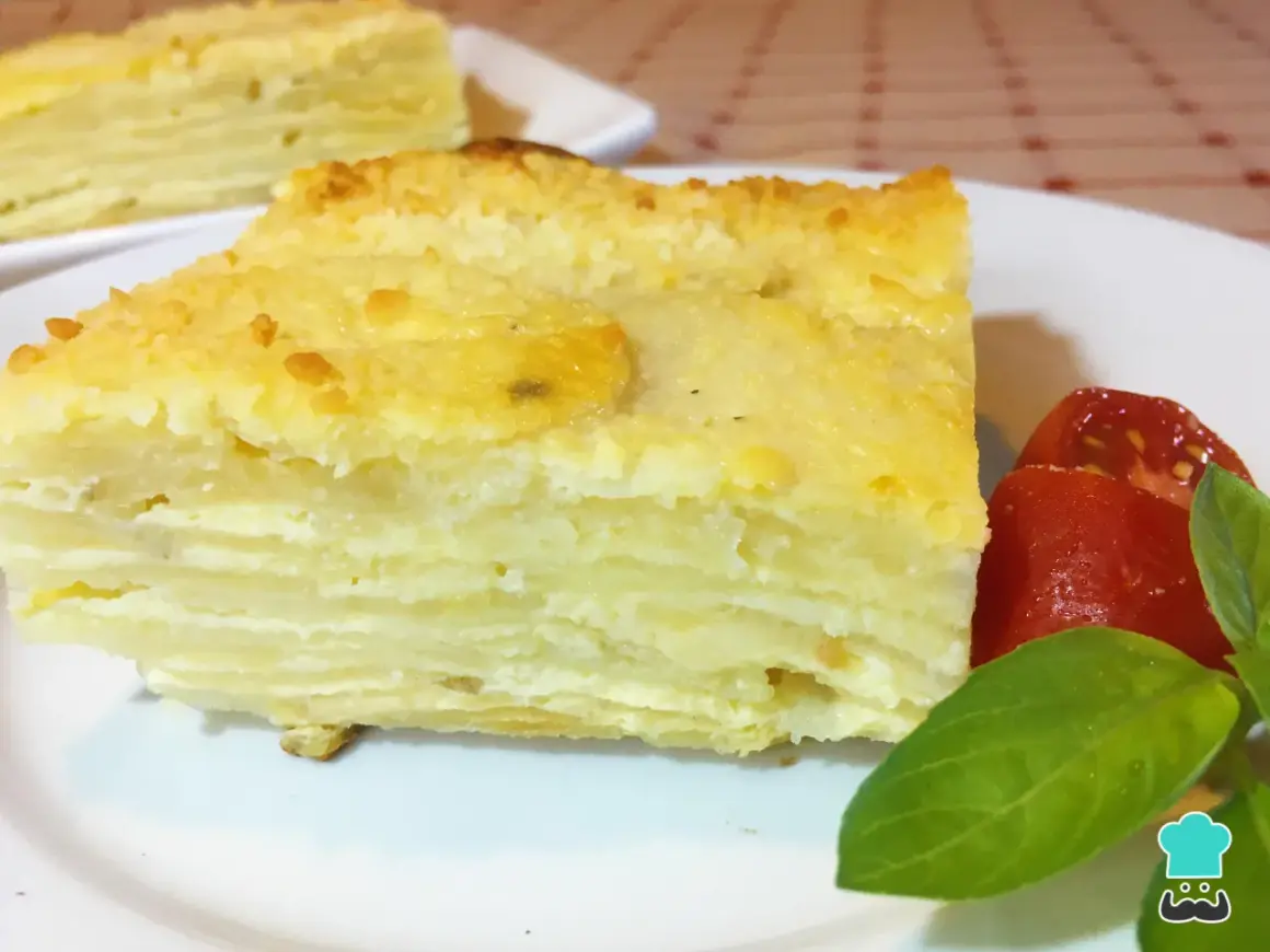 Delicioso pastel de papa en capas, un milhojas de patata gratinado, servido con tomates y albahaca.