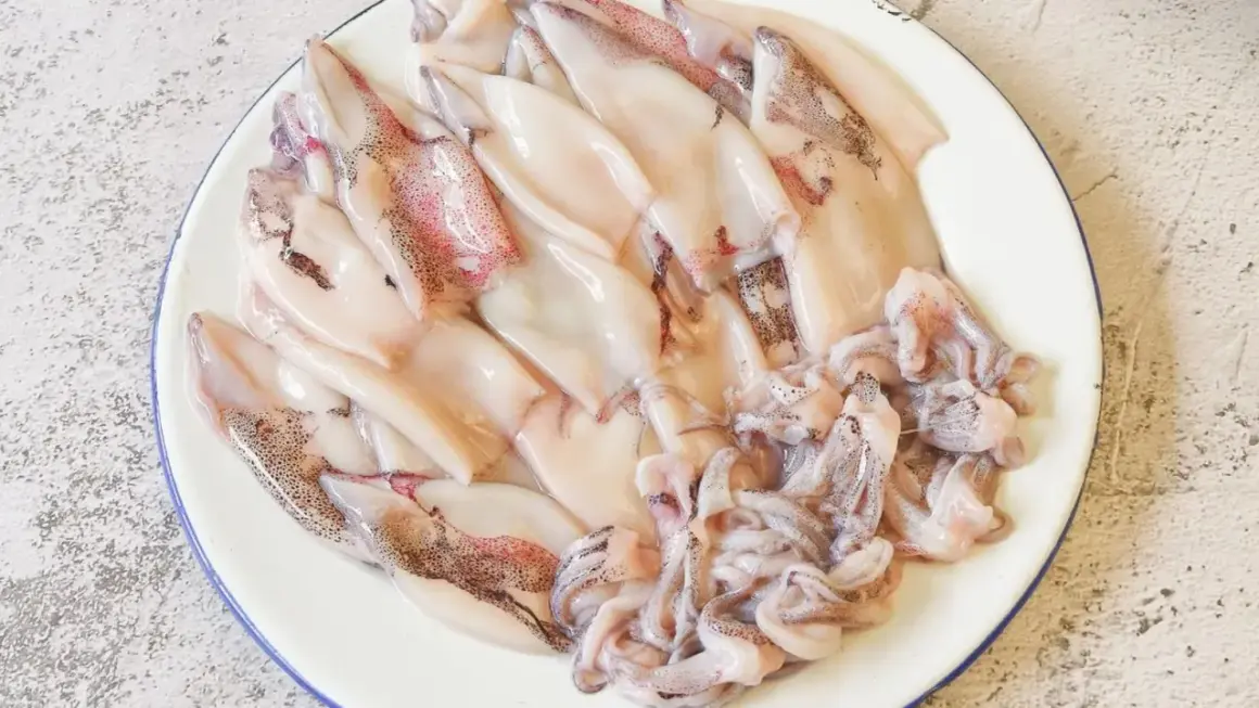 Plato con chipirones limpios y tentáculos listos para freír. Se aprecian sus manchas oscuras y tonos rosados.