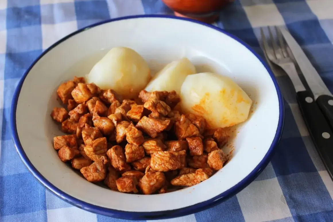 Plato de zorza con patatas, servido en un cuenco blanco con borde azul sobre un mantel de cuadros azules.