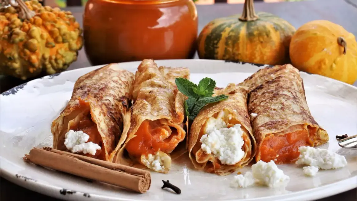 Rollitos de crepes rellenos de calabaza y queso fresco, decorados con menta y canela. Ideales para recetas con calabaza.