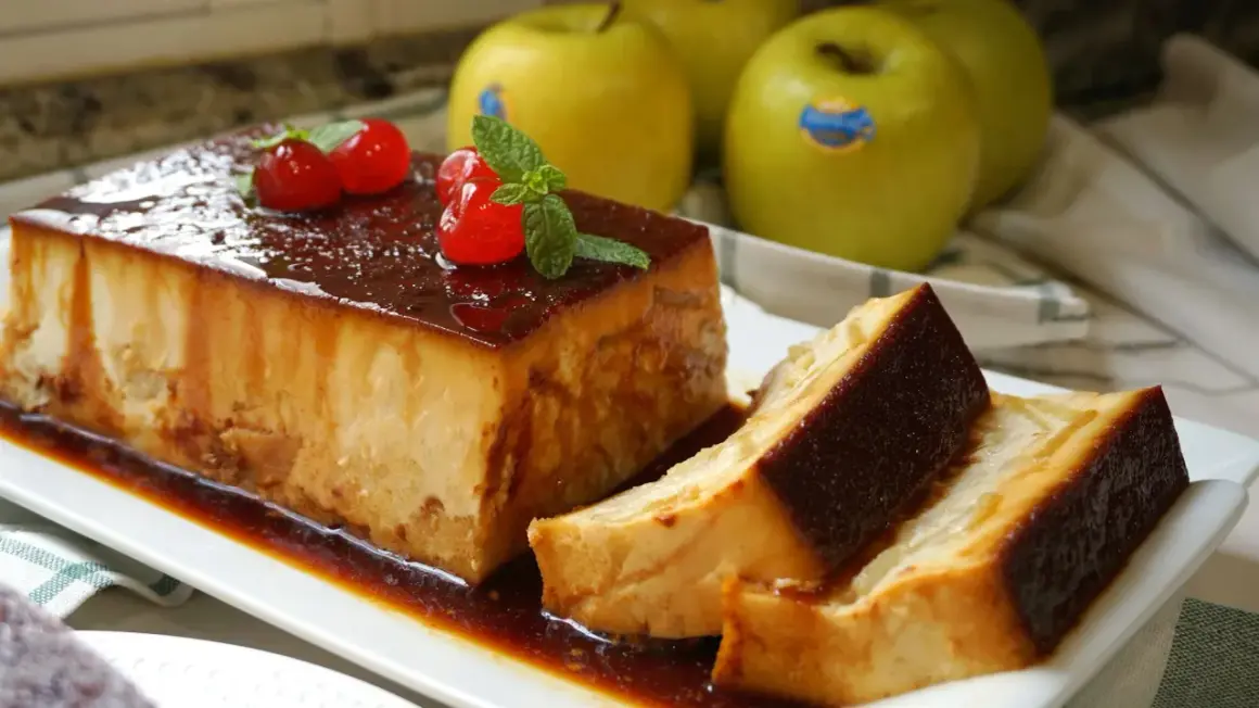 Delicioso pudin de manzana con caramelo, decorado con cerezas y menta. Manzanas verdes al fondo.