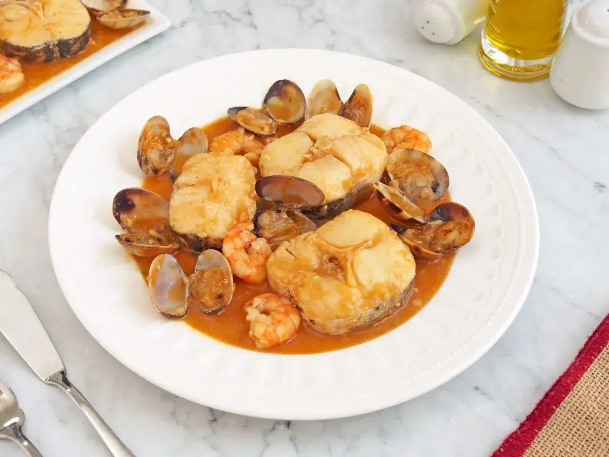 Merluza a la marinera con gambas y almejas en una salsa sabrosa. Un plato delicioso y tradicional.
