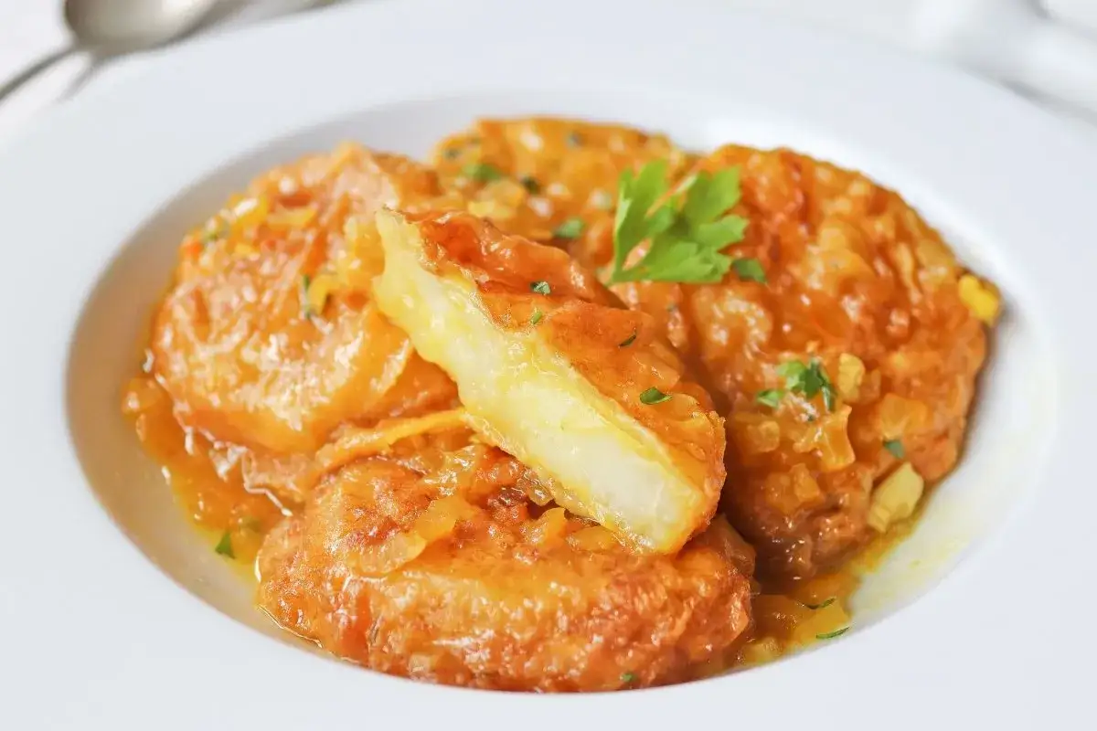 Patatas a la importancia, un plato que demuestra la gran importancia de las patatas en la cocina, servidas en una salsa dorada con perejil.