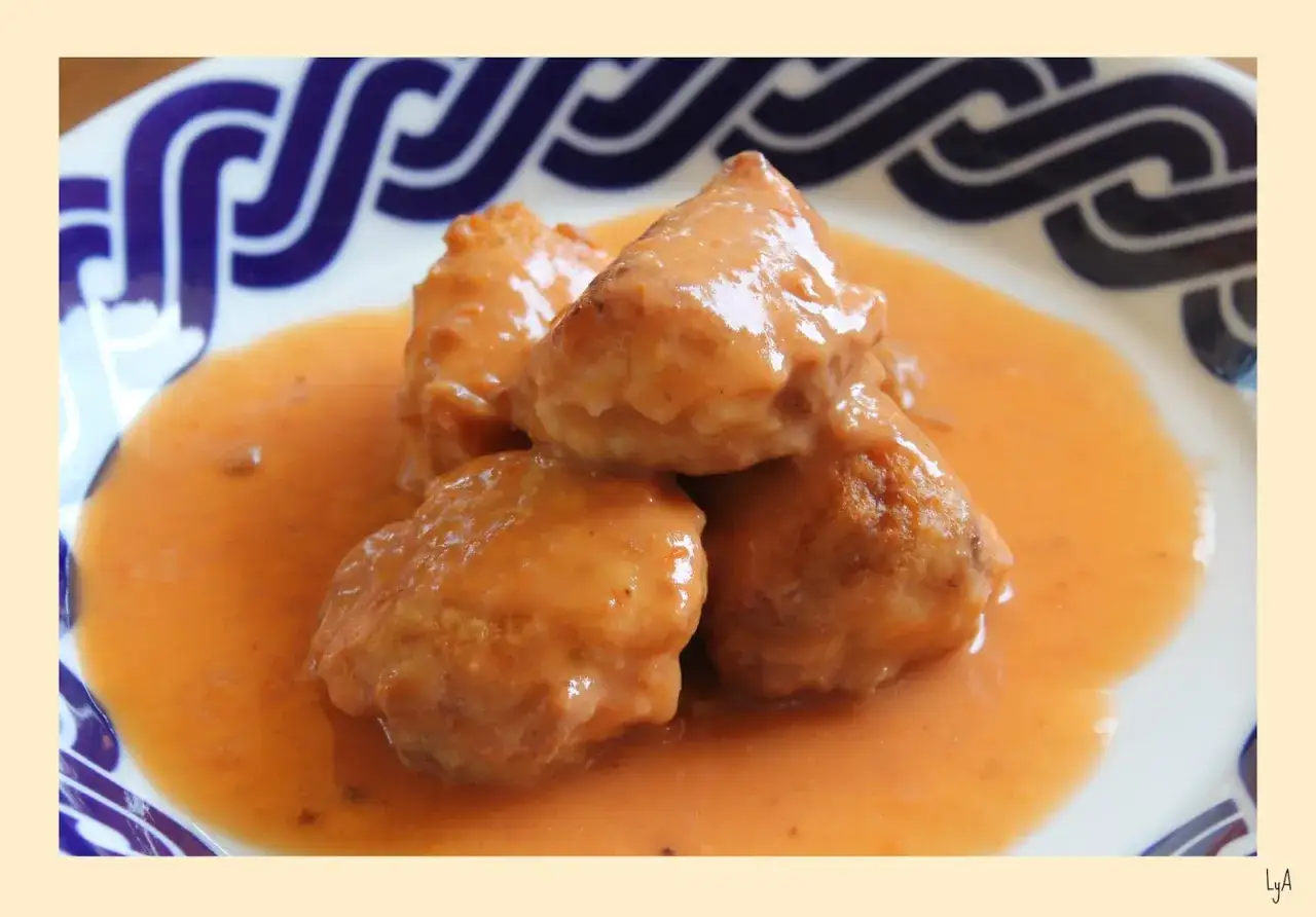 Albondigas de rape en salsa cremosa, servidas en un plato con borde azul.