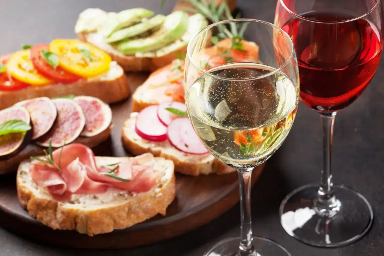 Tabla con variedad de bruschettas y copas de vino. Un picoteo fácil y rápido para disfrutar.