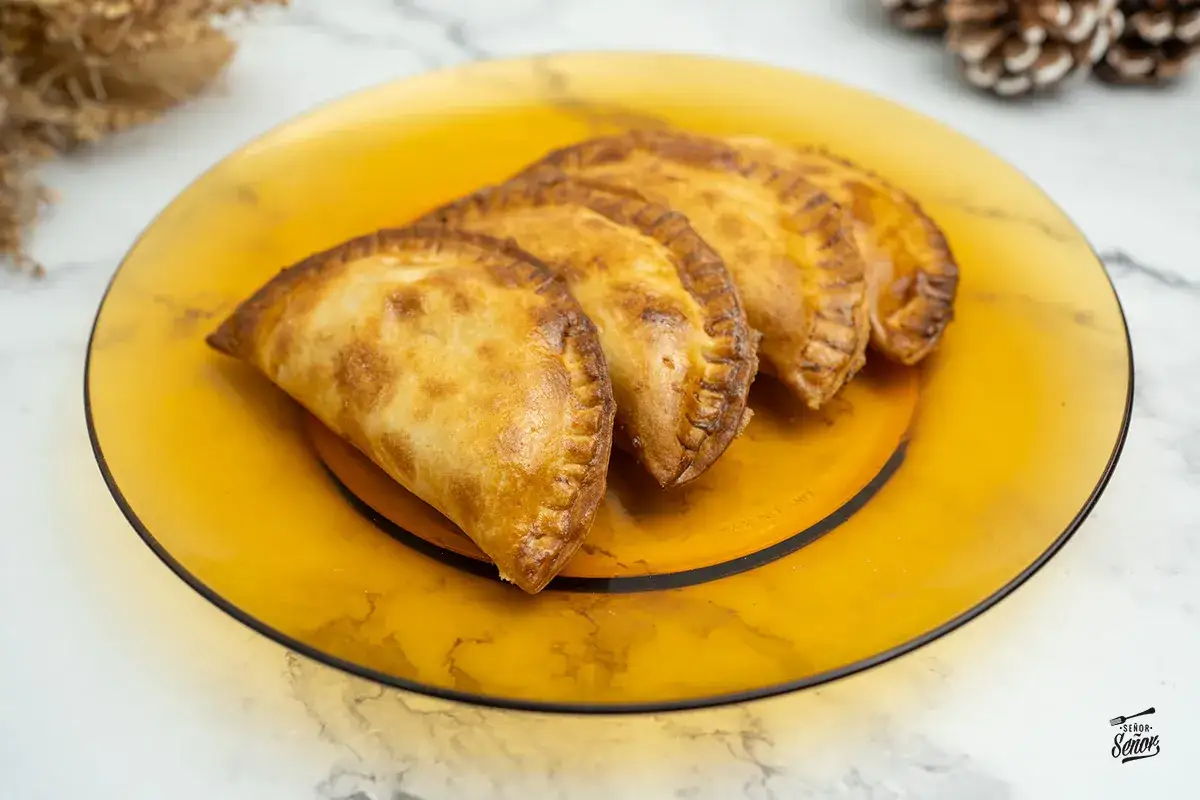 Empanadillas doradas y crujientes, reci&eacute;n hechas en freidora de aire, servidas en un plato &aacute;mbar.