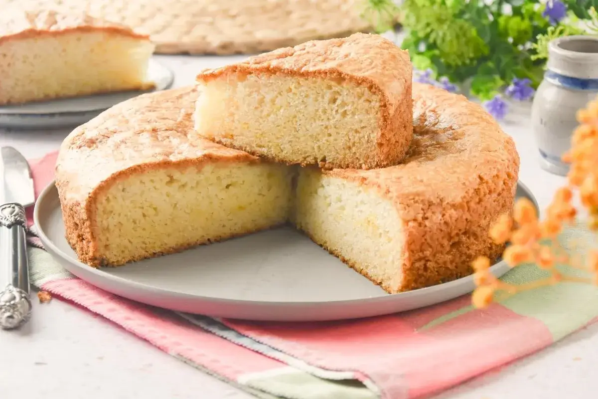 Bizcocho sin huevo esponjoso y dorado, cortado en porciones sobre un plato gris. Un postre ligero y delicioso.