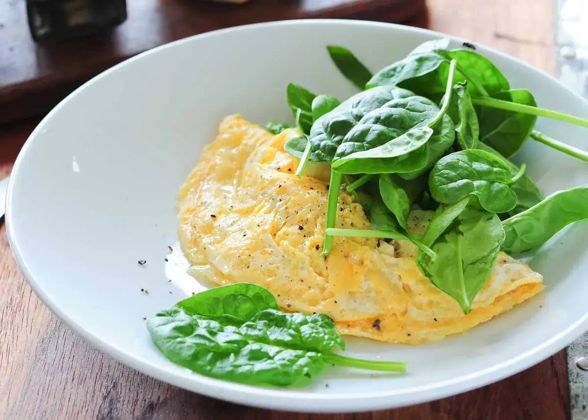 Tortilla francesa esponjosa con espinacas frescas, un desayuno ligero y saludable.