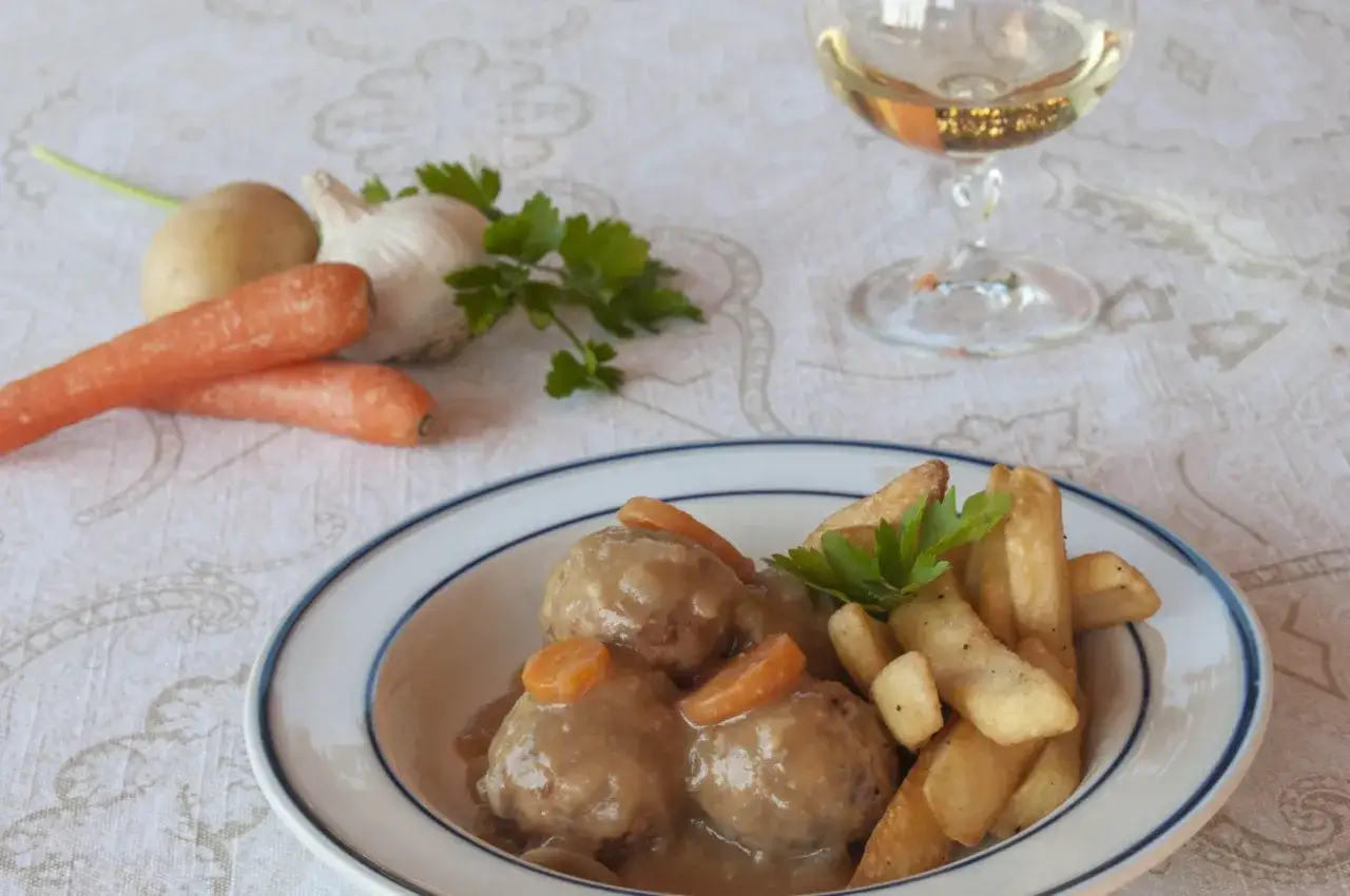 Alb&oacute;ndigas en salsa argui&ntilde;ano, jugosas y caseras, acompa&ntilde;adas de patatas fritas y un toque de perejil.