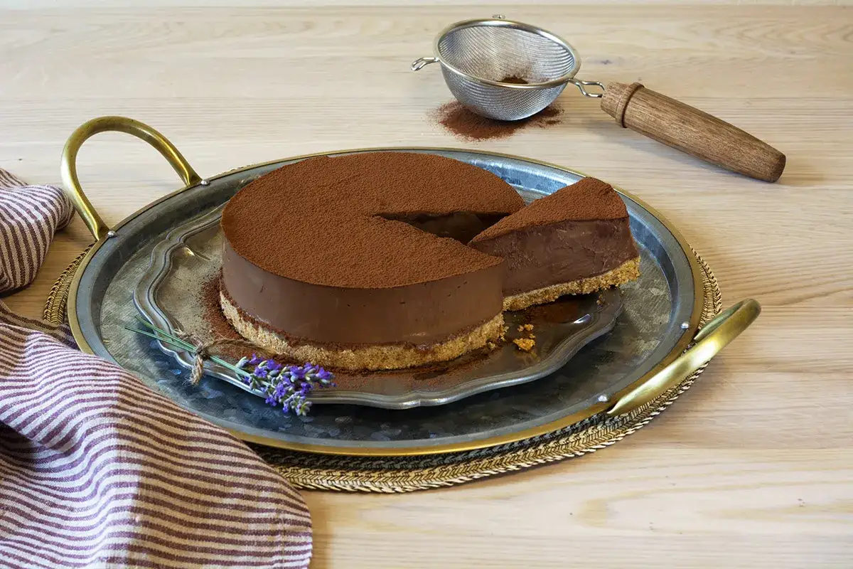 Deliciosa marquesa de chocolate, espolvoreada con cacao, servida en bandeja met&aacute;lica con un toque de lavanda.